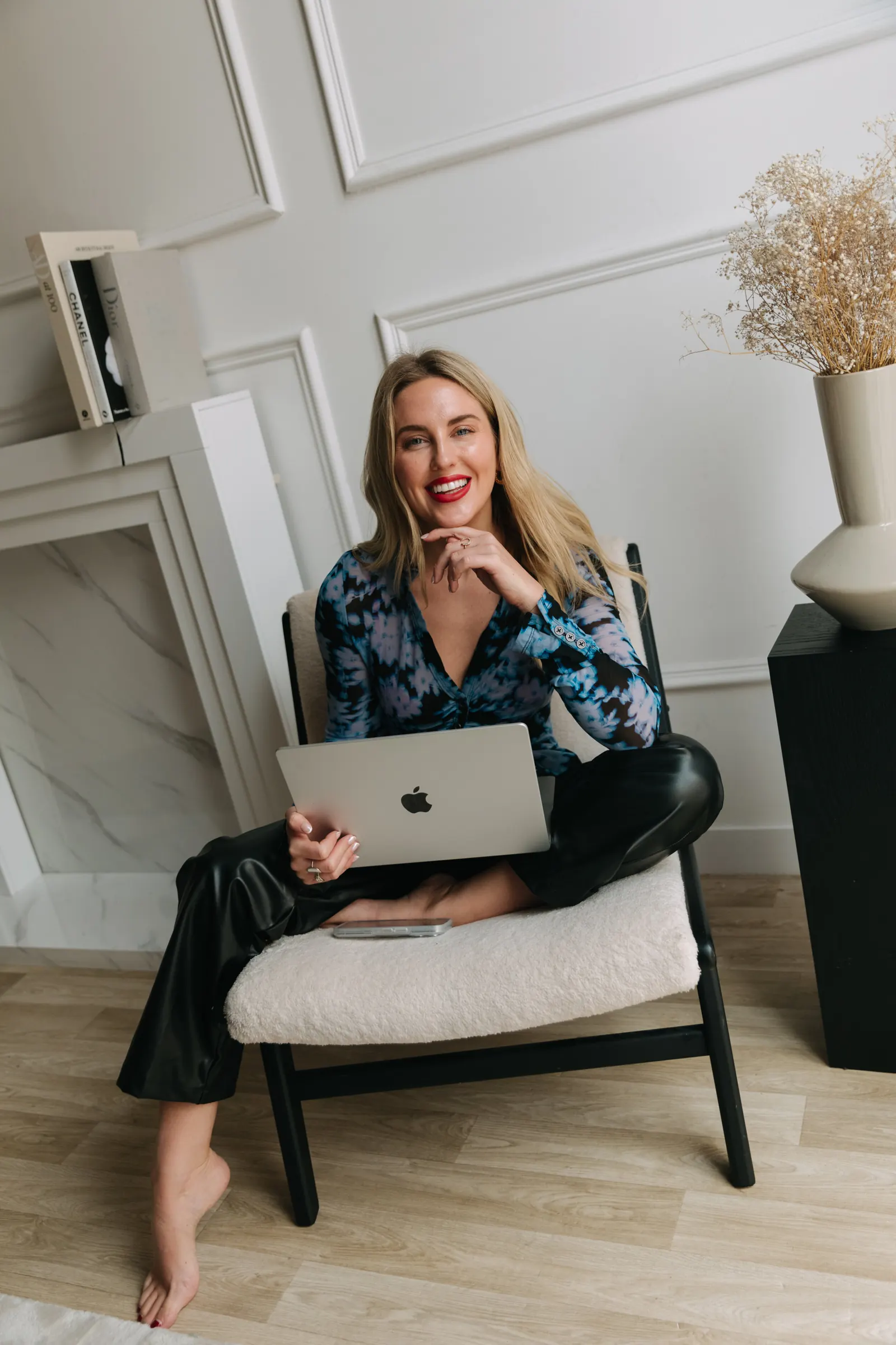 Emily in a blue floral top sitting cross-legged with a laptop