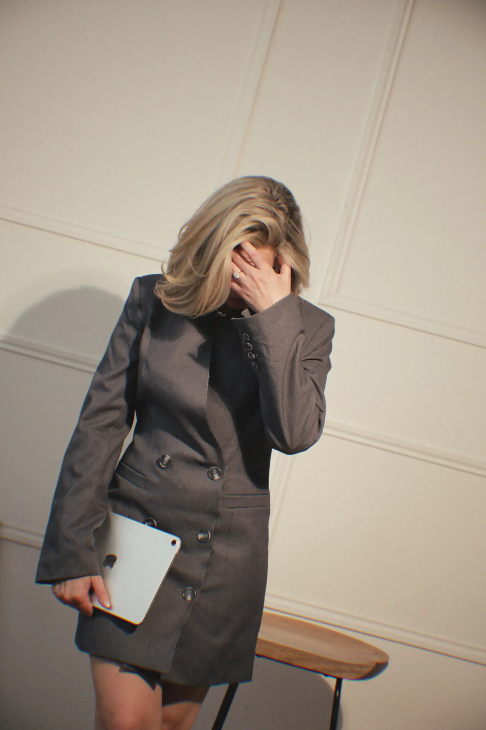 Emily in a grey blazer dress holding a tablet