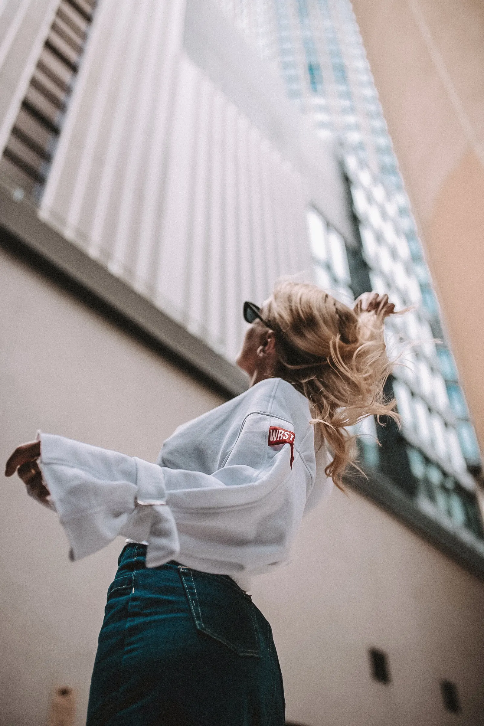 Emily looking up at a glass building in a white top