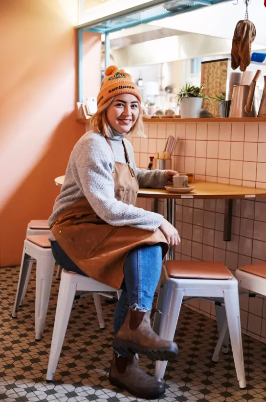 Elizabeth, chef, in a beanie at a cafe counter