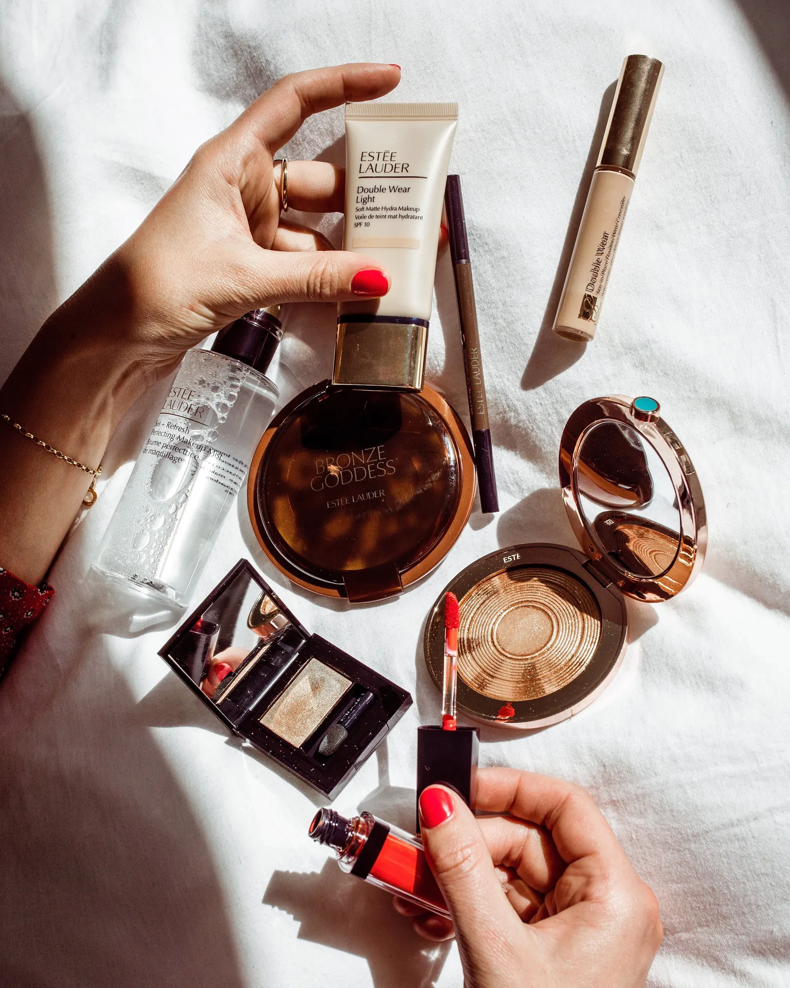 Beauty products flat lay with hands holding a foundation bottle